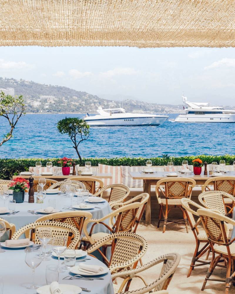 Golden sunset illuminates a vibrant beachside gathering with guests mingling by the water.