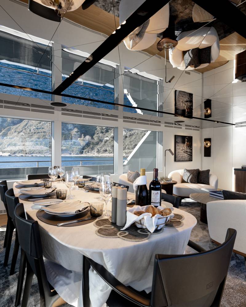 A modern and spacious dining room with a large window overlooking a scenic mountain landscape, featuring a set table with elegant tableware and decor.