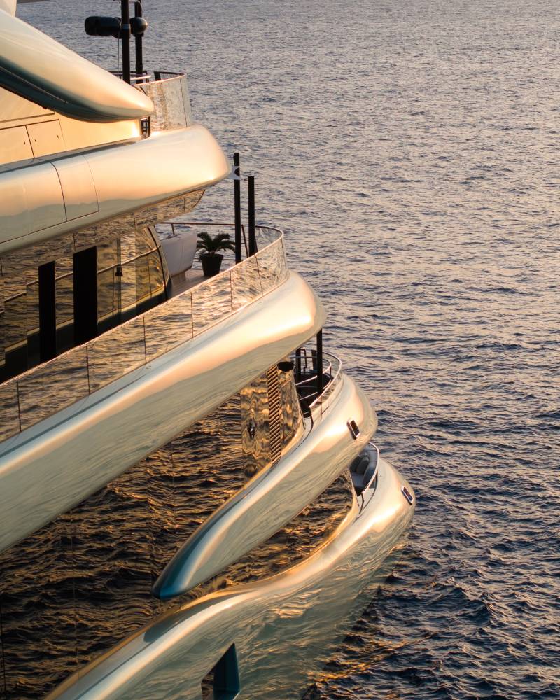 A sleek, golden yacht glides across calm, sun-drenched waters.