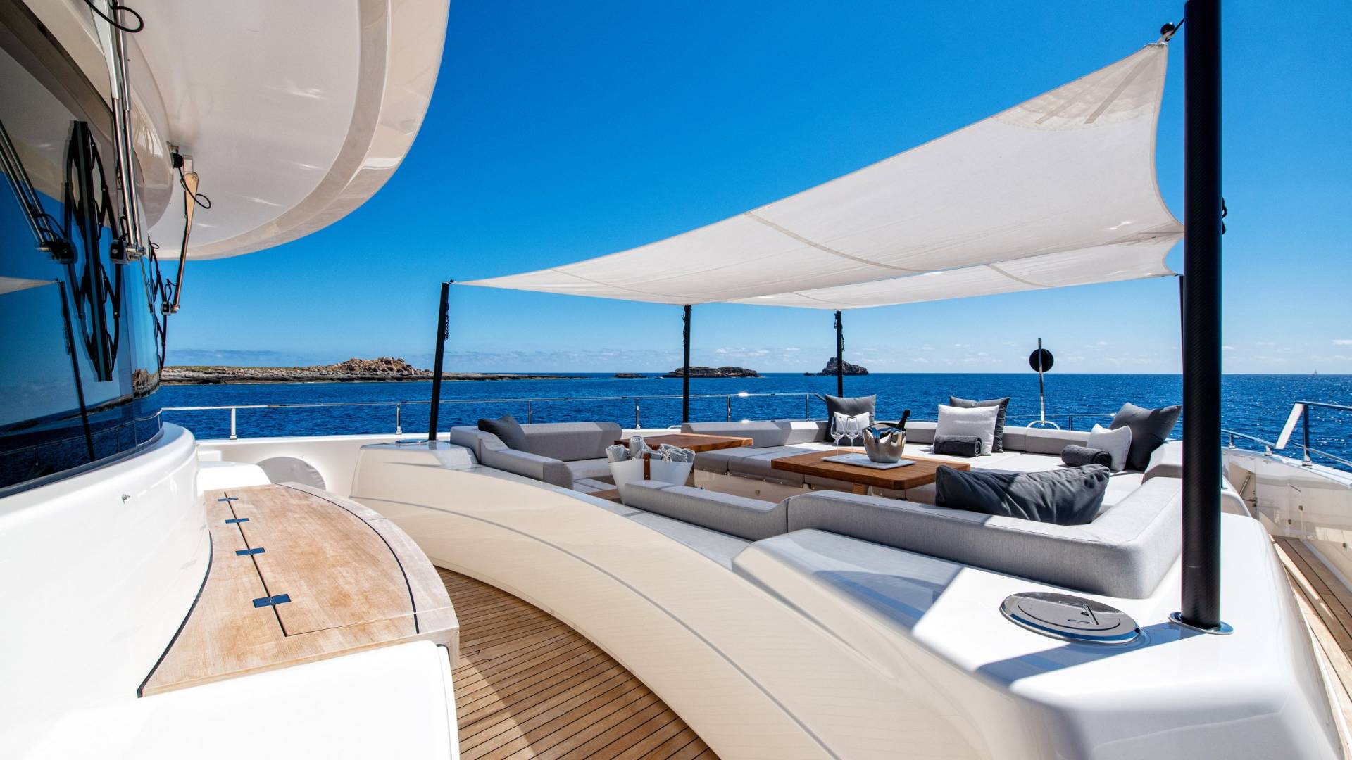 Luxurious yacht seating offers a prime spot to enjoy the sun-drenched Mediterranean Sea and distant rocky islands.