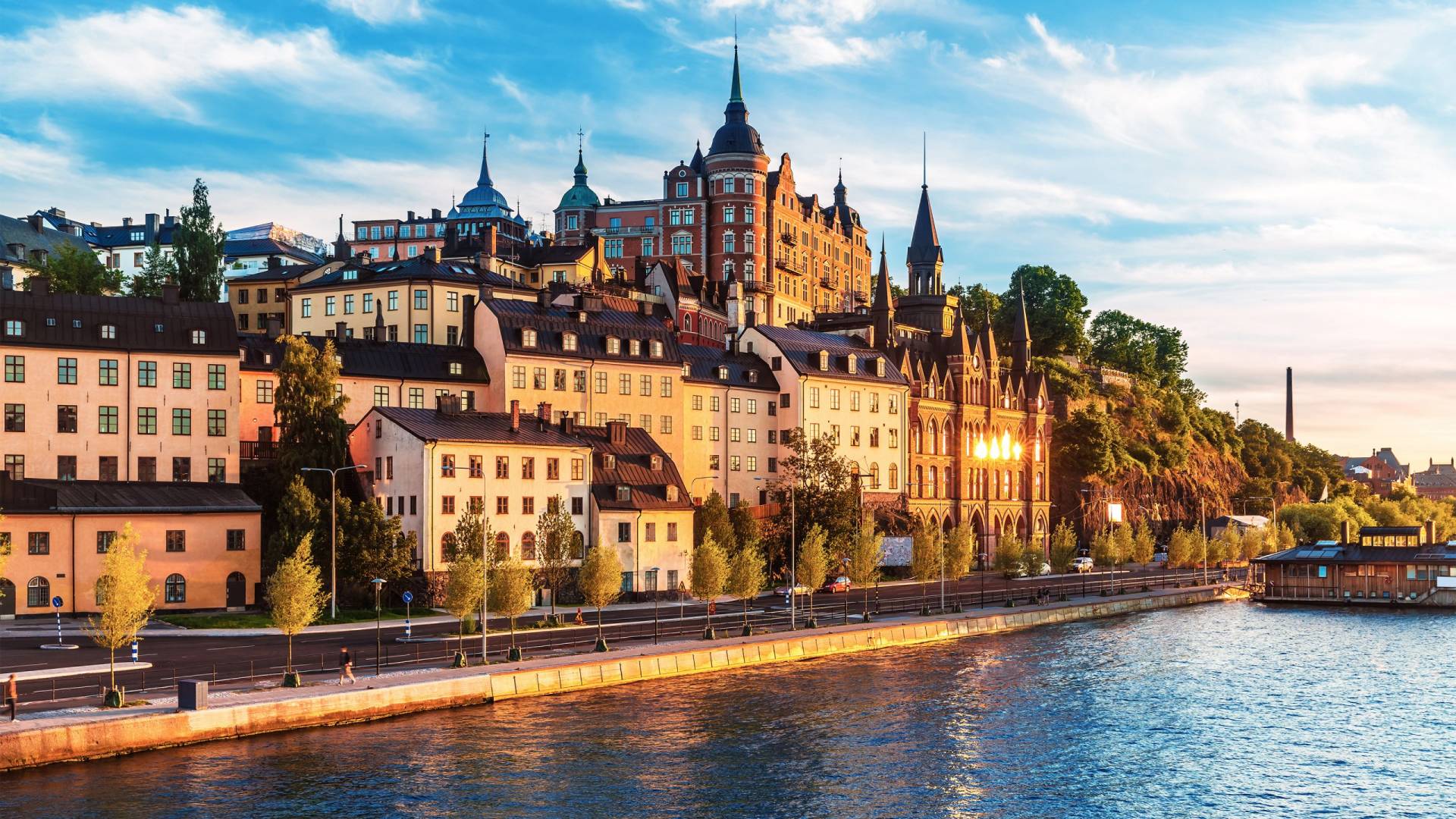 Golden hour light bathes the historic waterfront buildings and their reflections in the shimmering water.