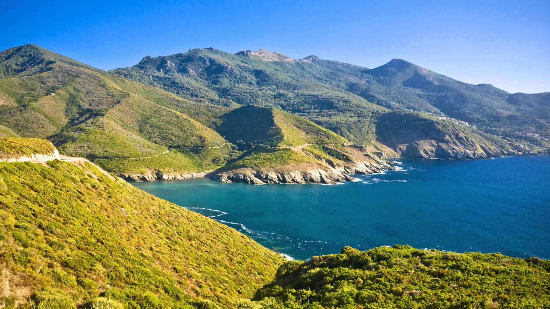 Lush green mountains cascade down to meet the vibrant blue waters of a secluded coastal cove.