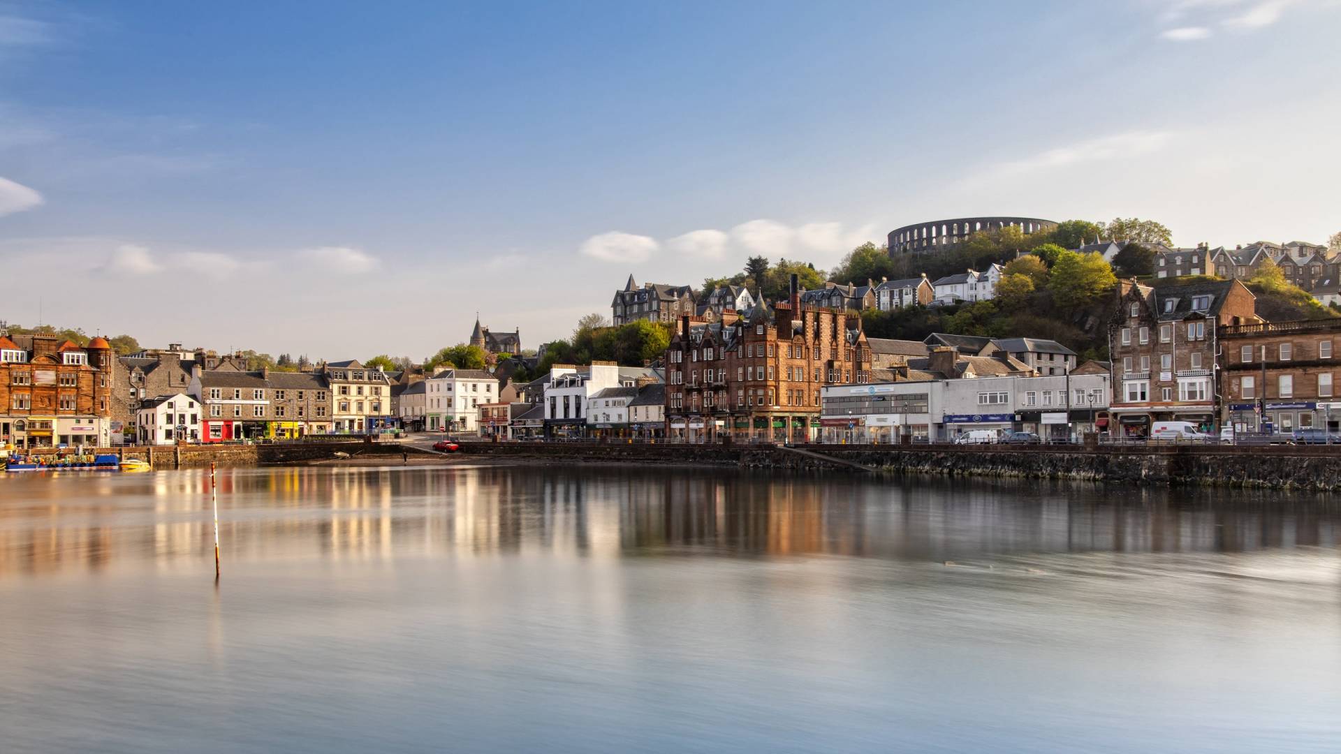 A picturesque waterfront town is bathed in the warm glow of the sun, reflecting on the calm water.