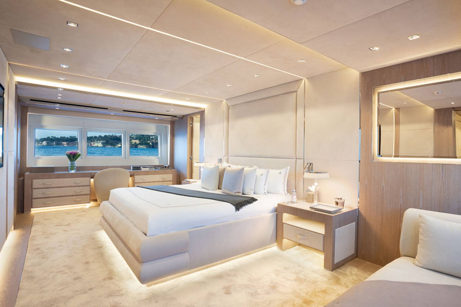 Luxurious yacht stateroom offers serene comfort with plush bedding, ambient lighting, and stunning ocean views.