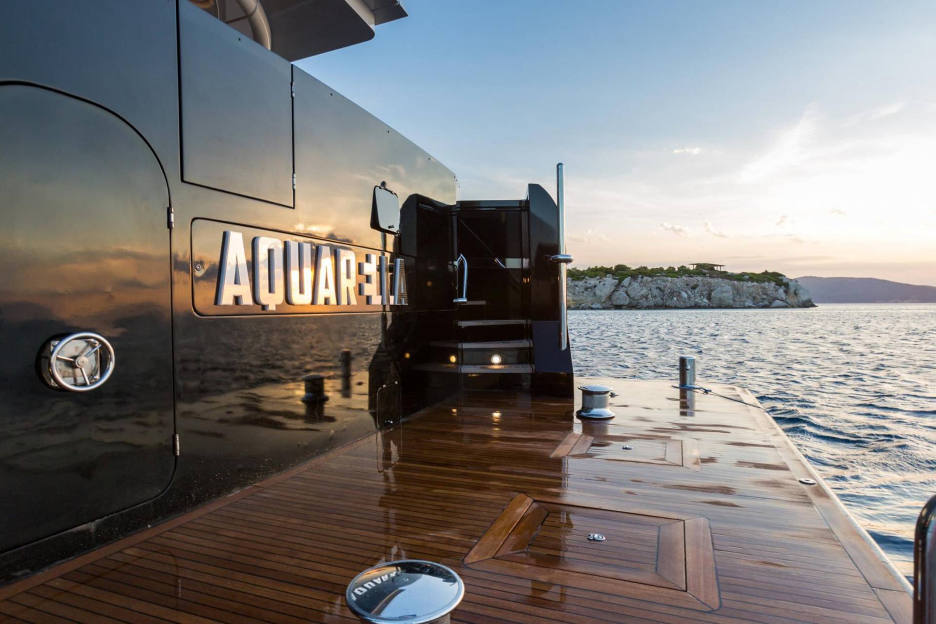 The luxurious yacht Aquarella glides across calm waters at sunset, its polished deck reflecting the warm hues of the sky.