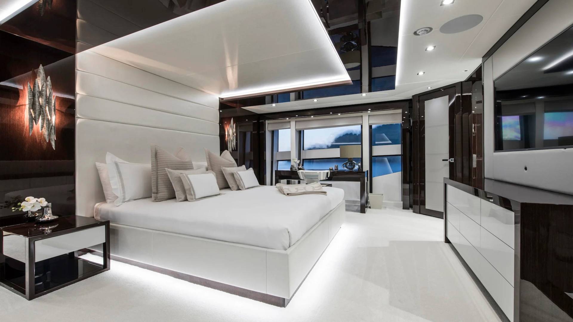 Luxurious yacht bedroom features a plush white bed, sleek dark wood accents, and ambient lighting for ultimate relaxation.