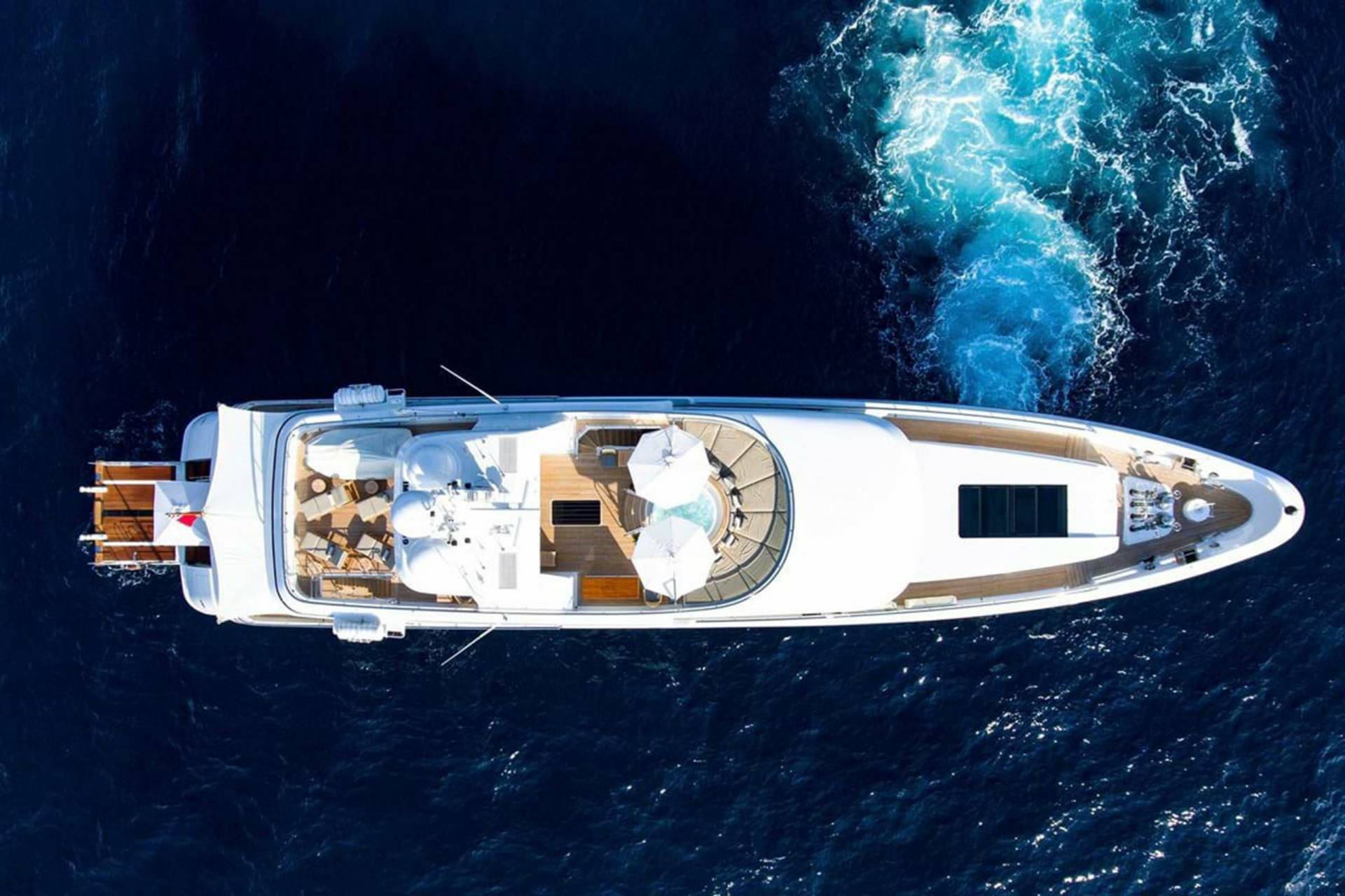 A luxurious white yacht glides through the deep blue ocean, leaving a trail of white wake.