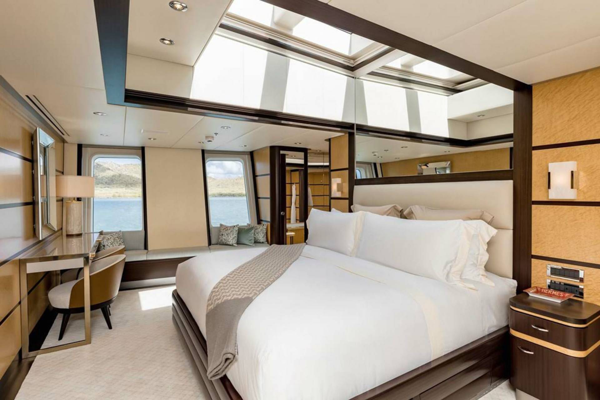 Luxurious yacht stateroom offers unparalleled comfort with a plush bed, expansive skylights, and stunning waterfront views.