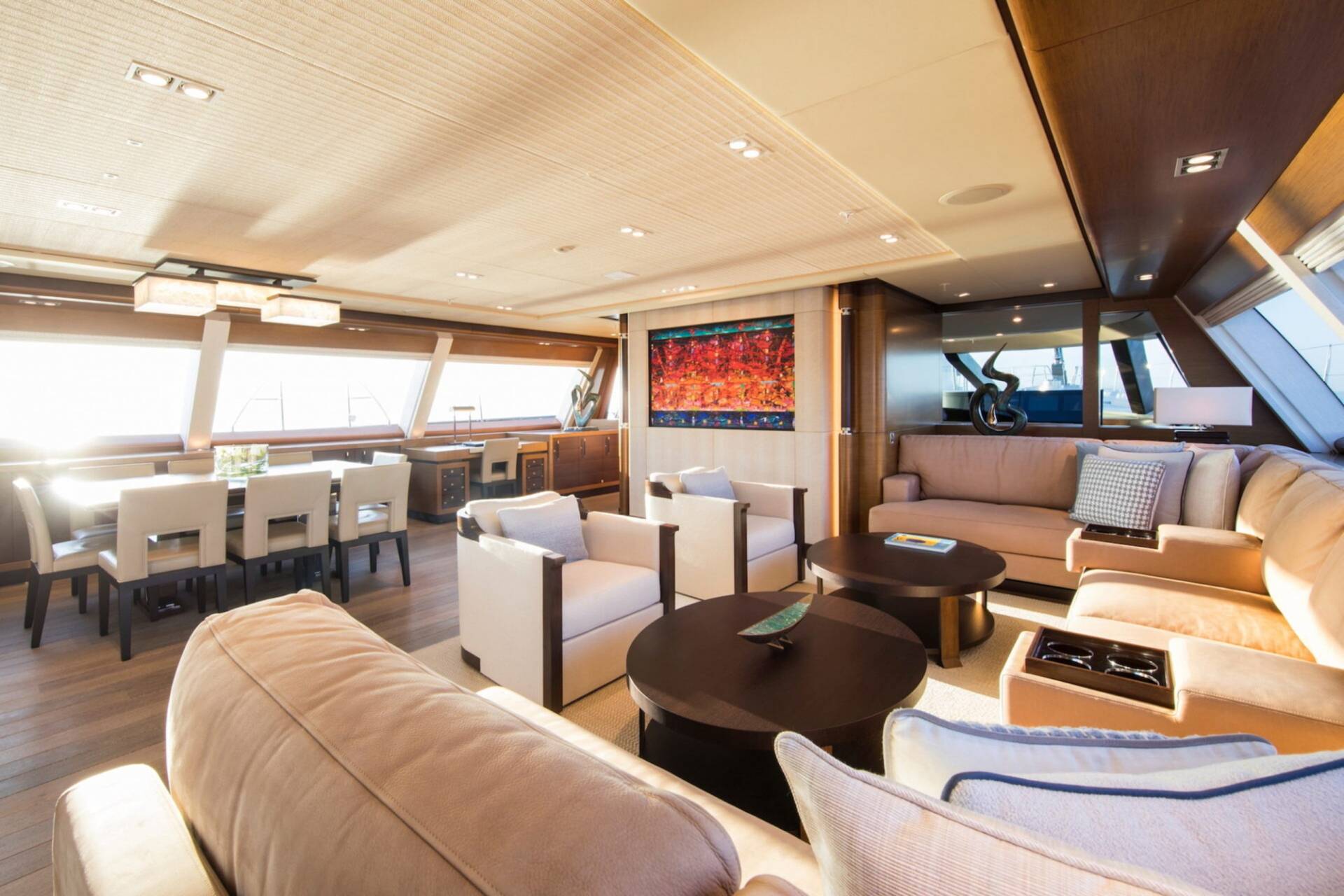 Luxurious yacht interiors feature a spacious lounge with comfortable seating, a dining area, and a vibrant artwork.
