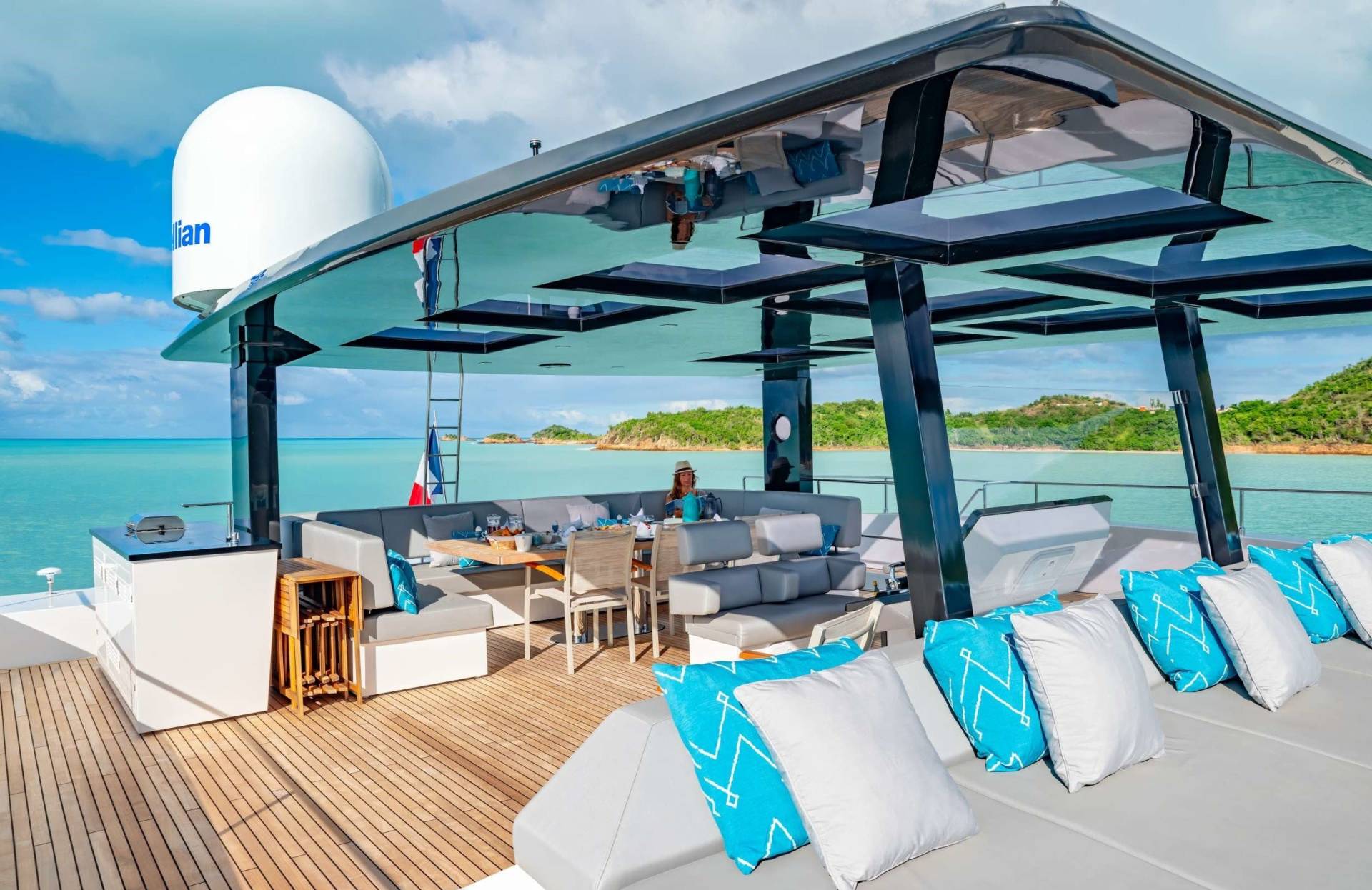 Enjoy a luxurious al fresco dining experience on the deck of a yacht surrounded by turquoise waters and lush islands.