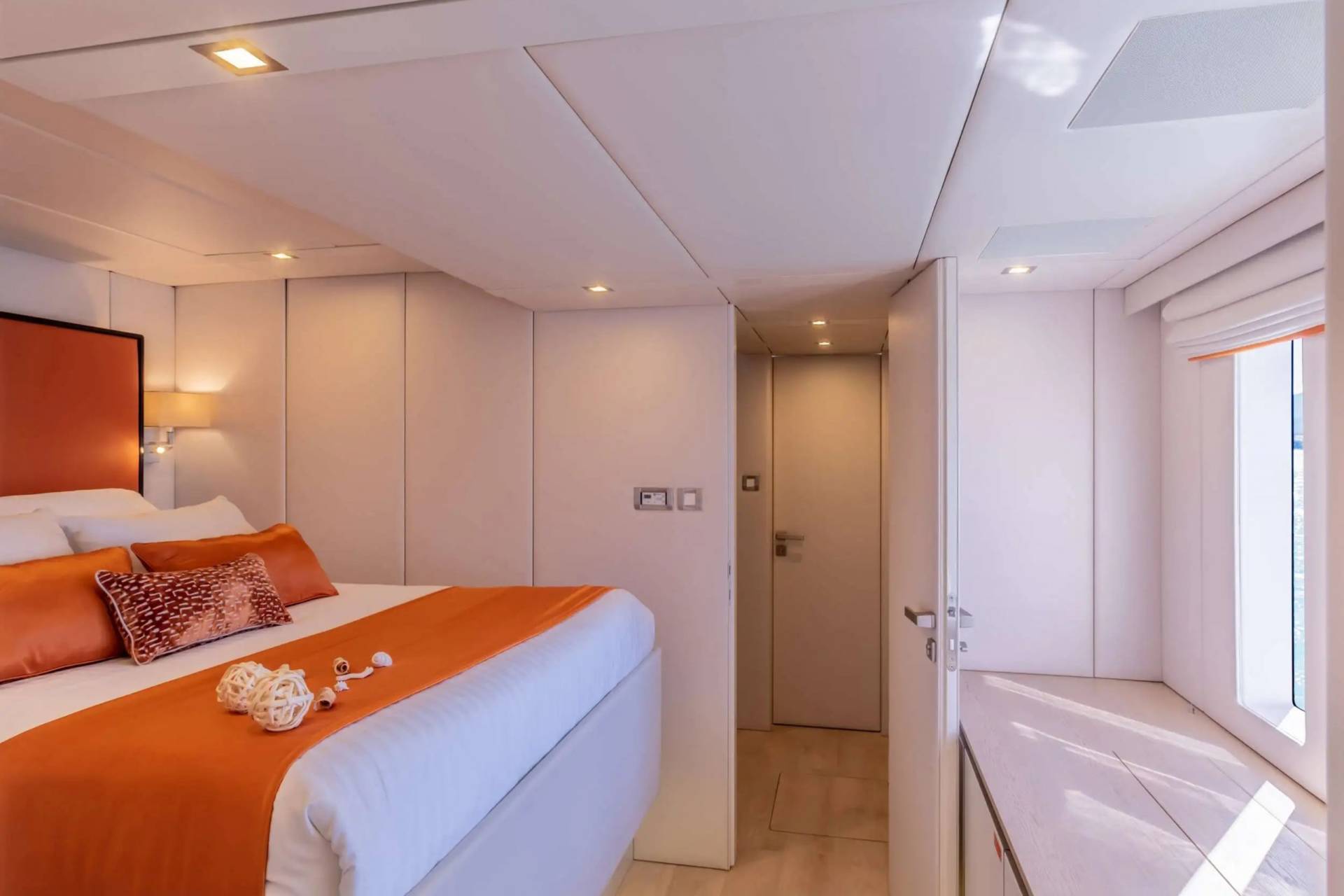 A modern bedroom with orange accents and a view of the water offers a serene escape.