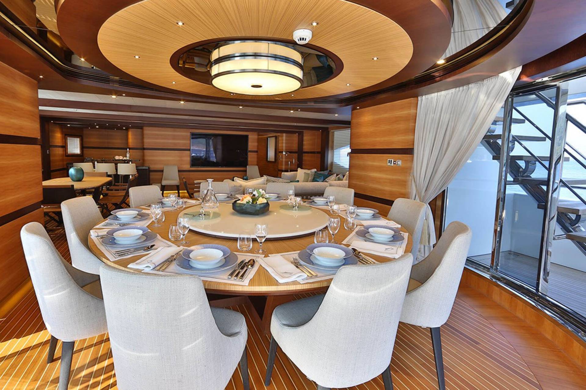 Elegant dining aboard a luxury yacht features a beautifully set table with a floral centerpiece and plush seating.