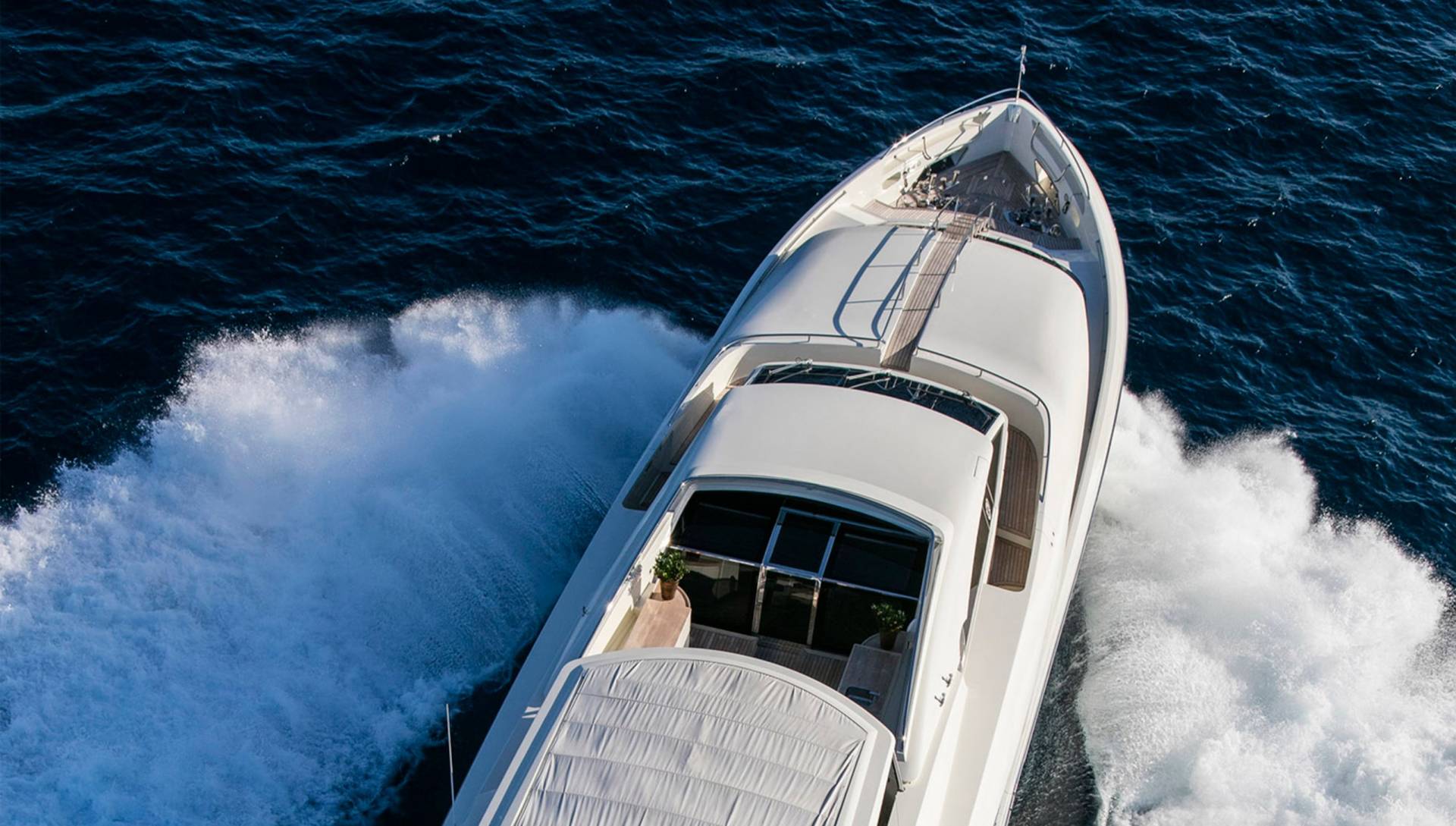 A sleek white yacht cuts through the deep blue ocean, leaving a powerful wake in its path.