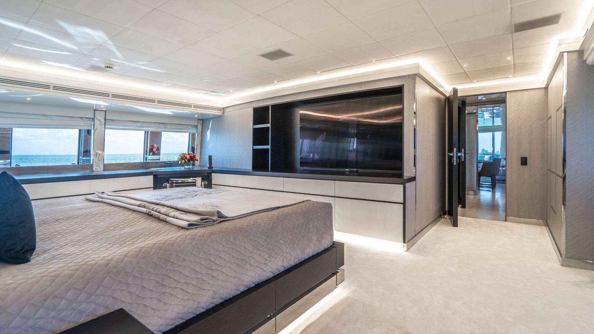 Luxurious yacht bedroom offers stunning ocean views and a sleek, modern entertainment center.