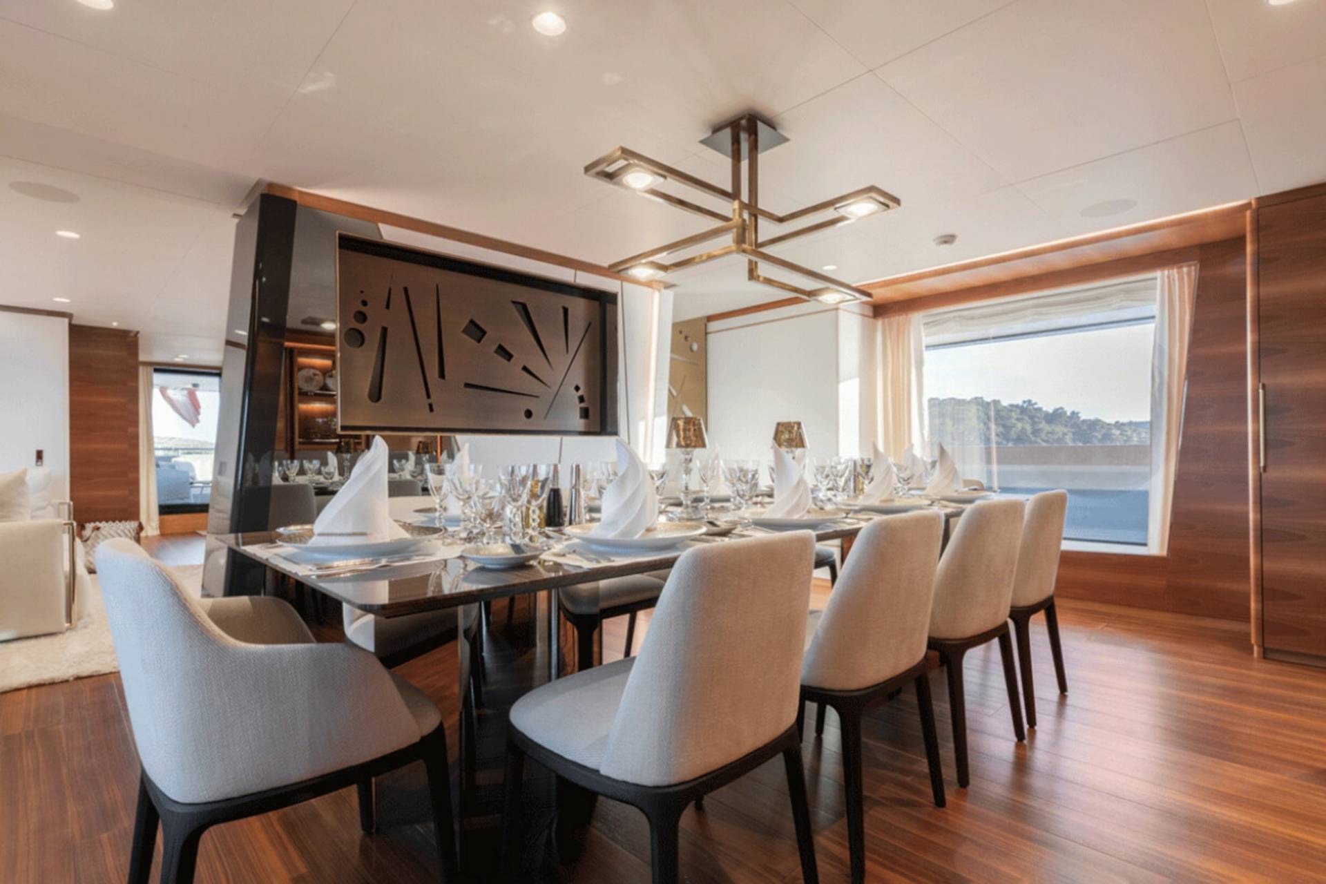 A luxurious yacht dining room is set for an elegant meal with a large table, comfortable chairs, and a scenic view.