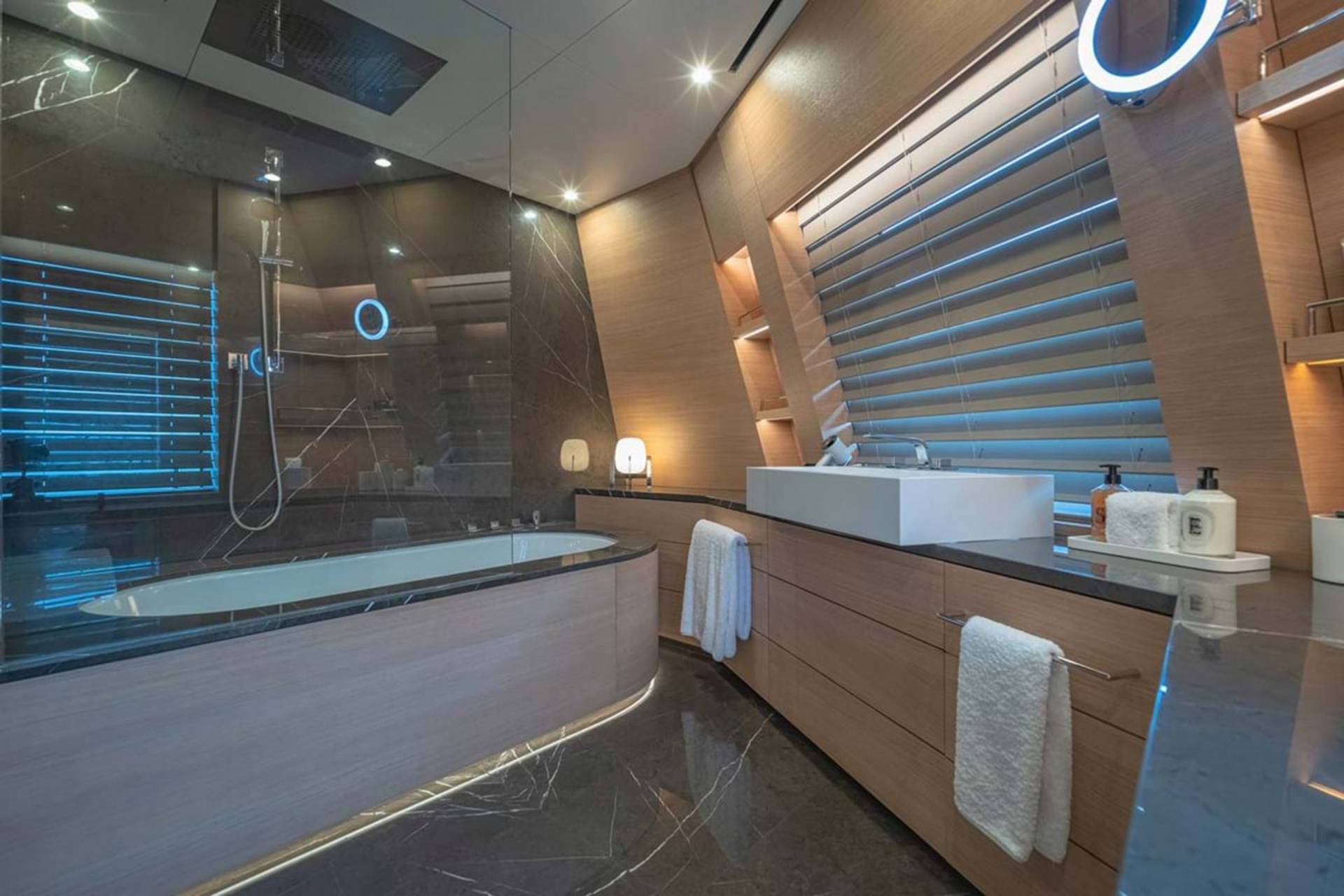 Luxurious modern bathroom features a sleek bathtub, a floating sink, and ambient blue lighting for a spa-like retreat.