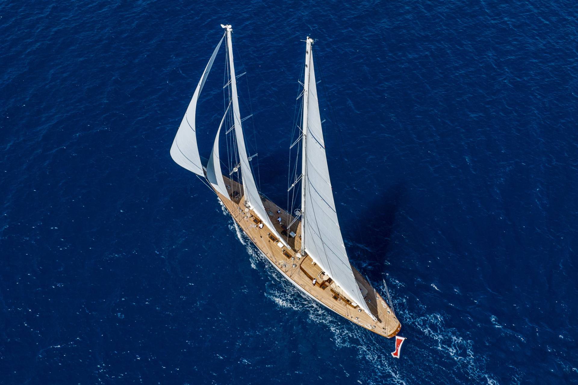 A majestic sailing yacht glides through the deep blue ocean, its white sails catching the wind.