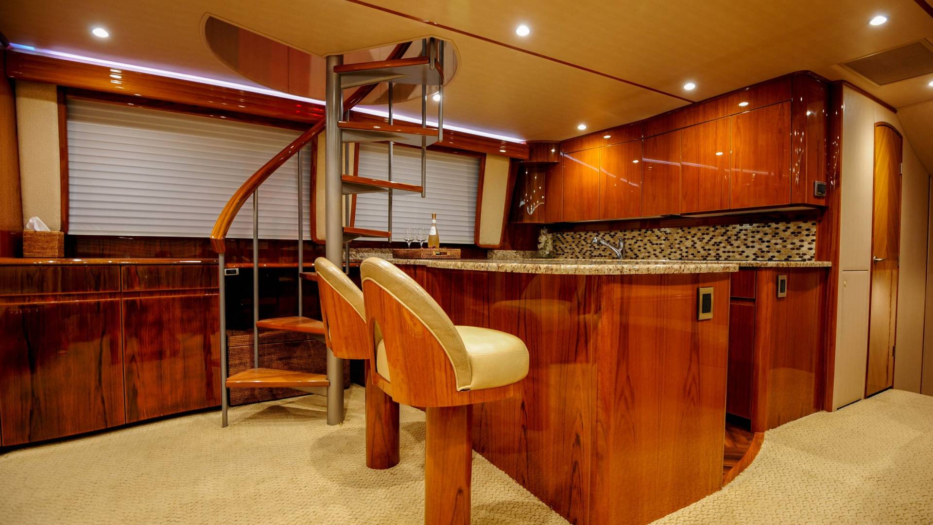 Luxurious wood cabinetry and a spiral staircase create an elegant galley on this yacht.