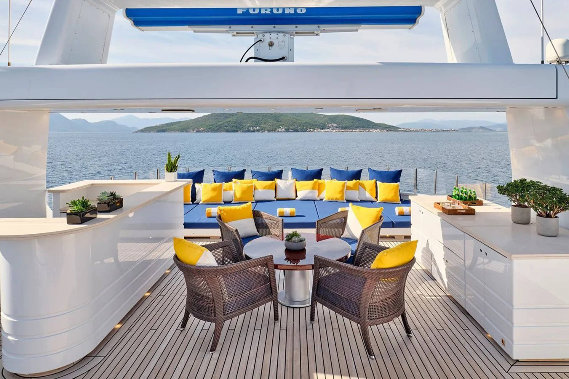 Relax on the spacious deck of this luxury yacht, surrounded by the serene blue sea and distant green hills.