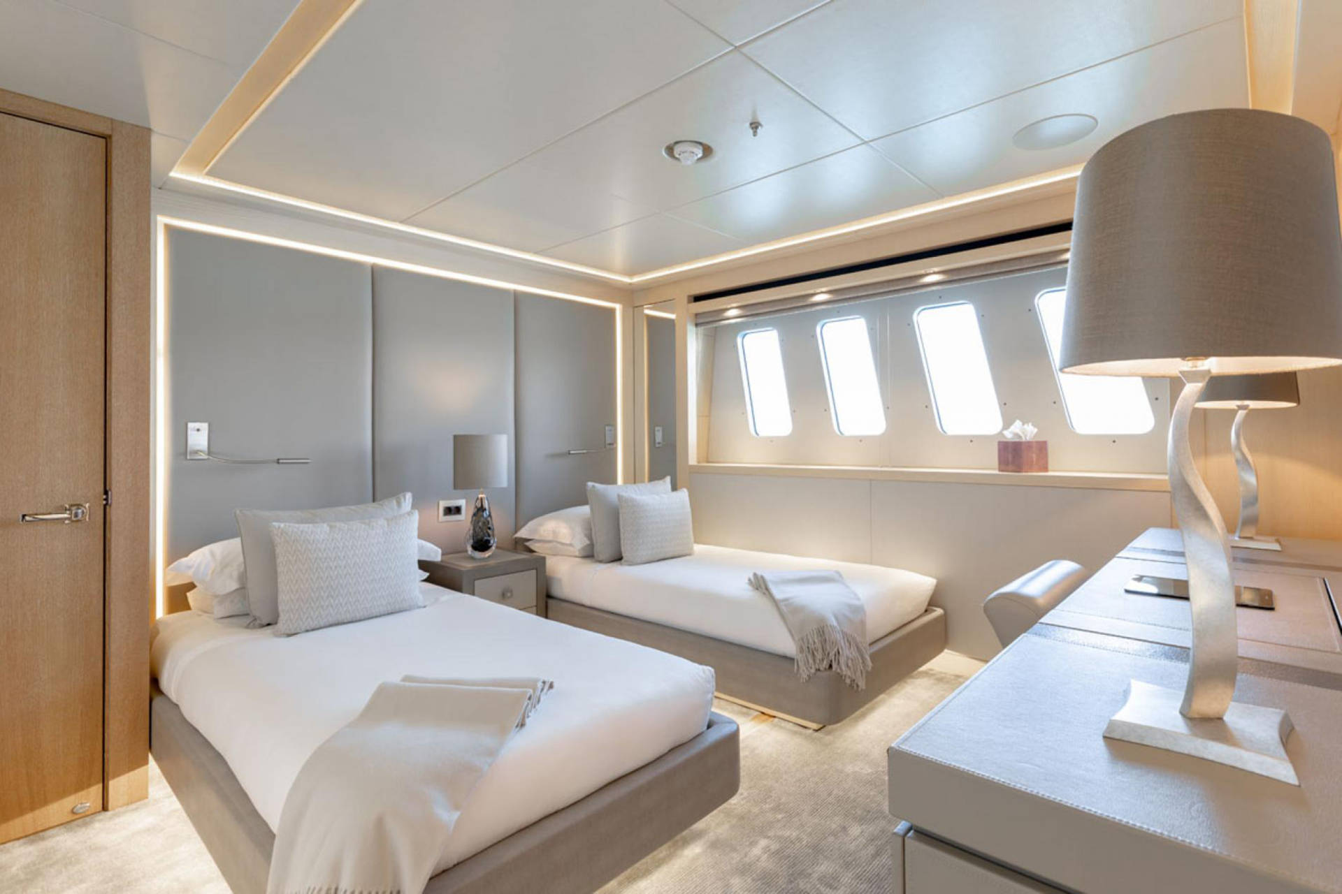 Luxurious twin beds with plush pillows and throws are bathed in the soft glow of bedside lamps and ambient lighting.