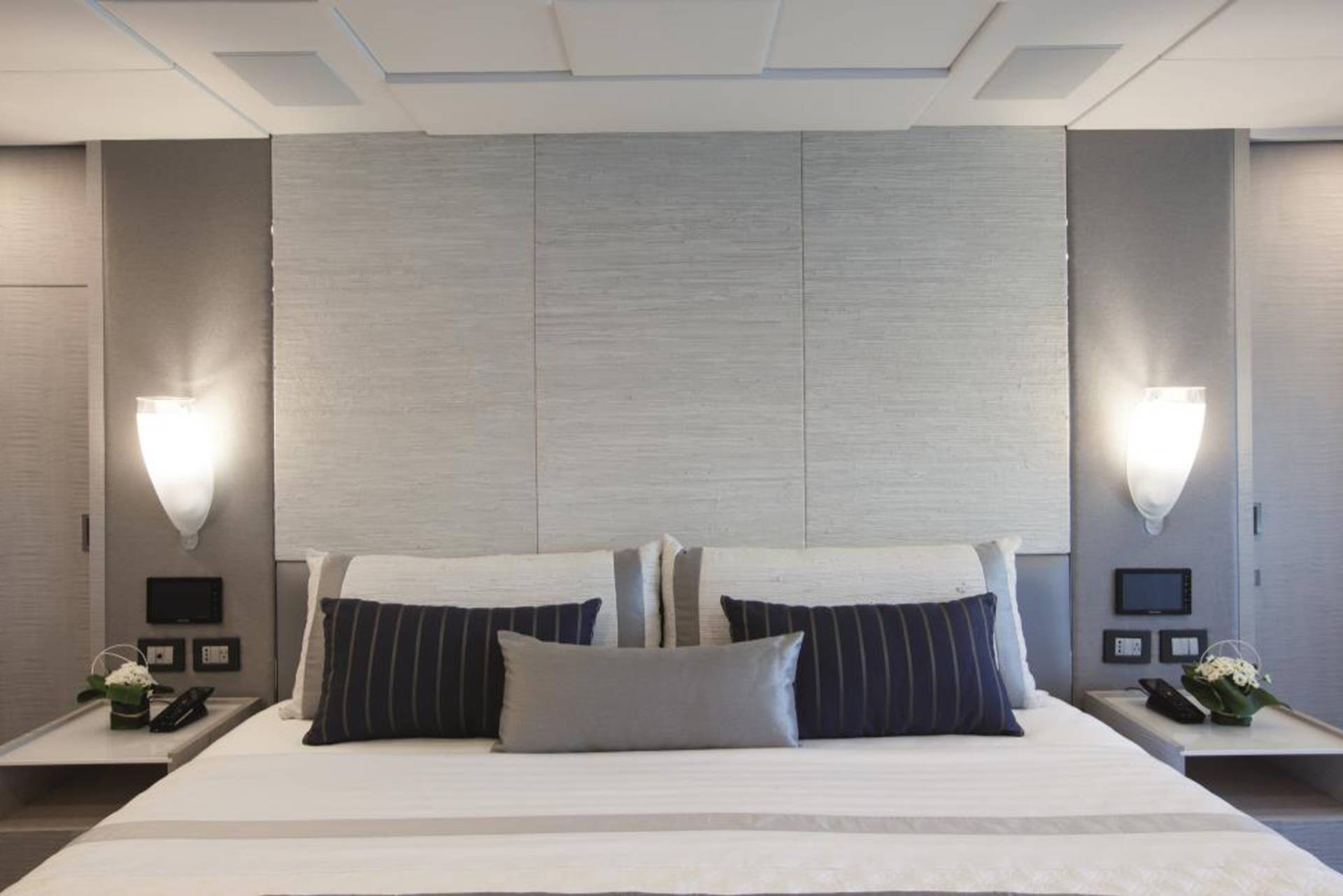 A modern and minimalist bedroom with a large bed, gray and white bedding, and wall panels providing a sleek and sophisticated ambiance.