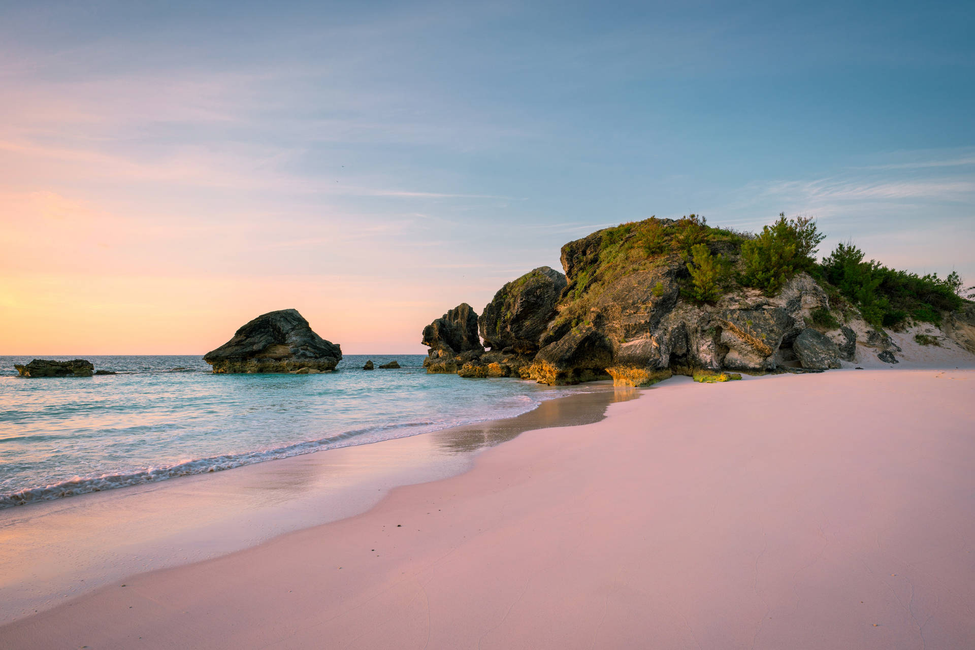 Soft pink sands meet the gentle turquoise waves of Bermuda at sunrise.
