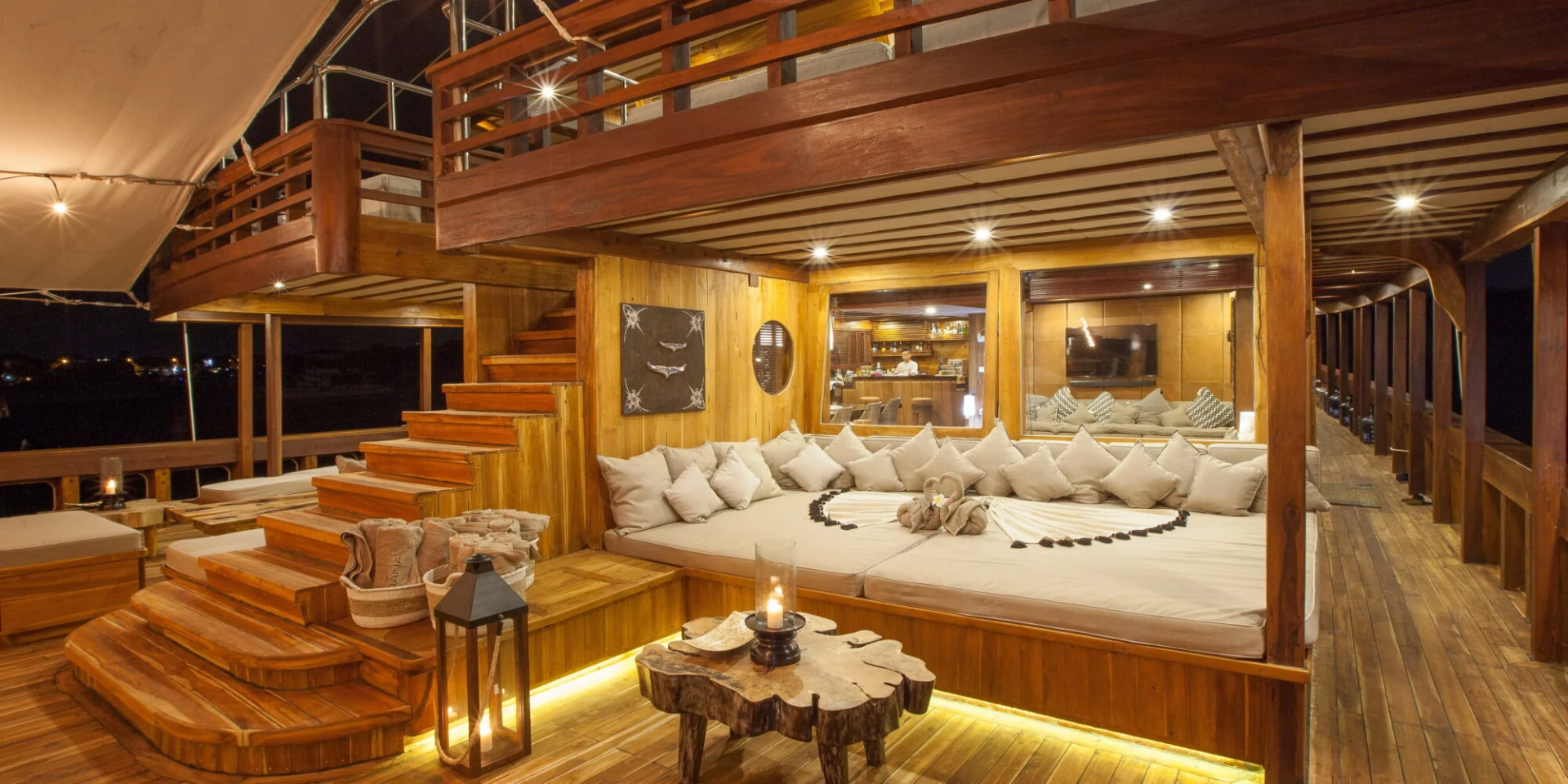 Relax on the plush daybed of this luxurious wooden deck, illuminated by soft lighting and the glow of candles.
