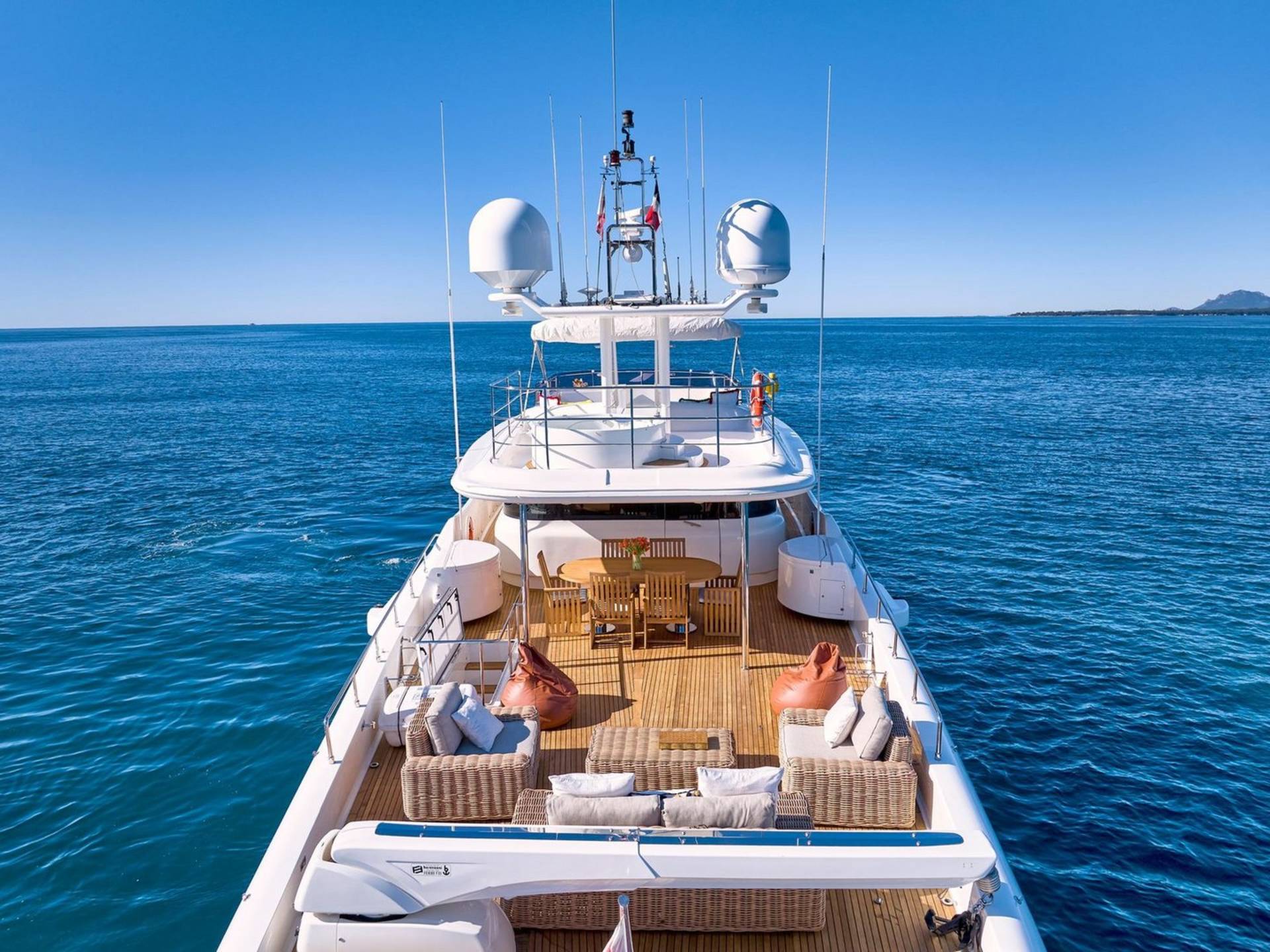A luxurious yacht glides through the calm blue ocean under a clear sky.