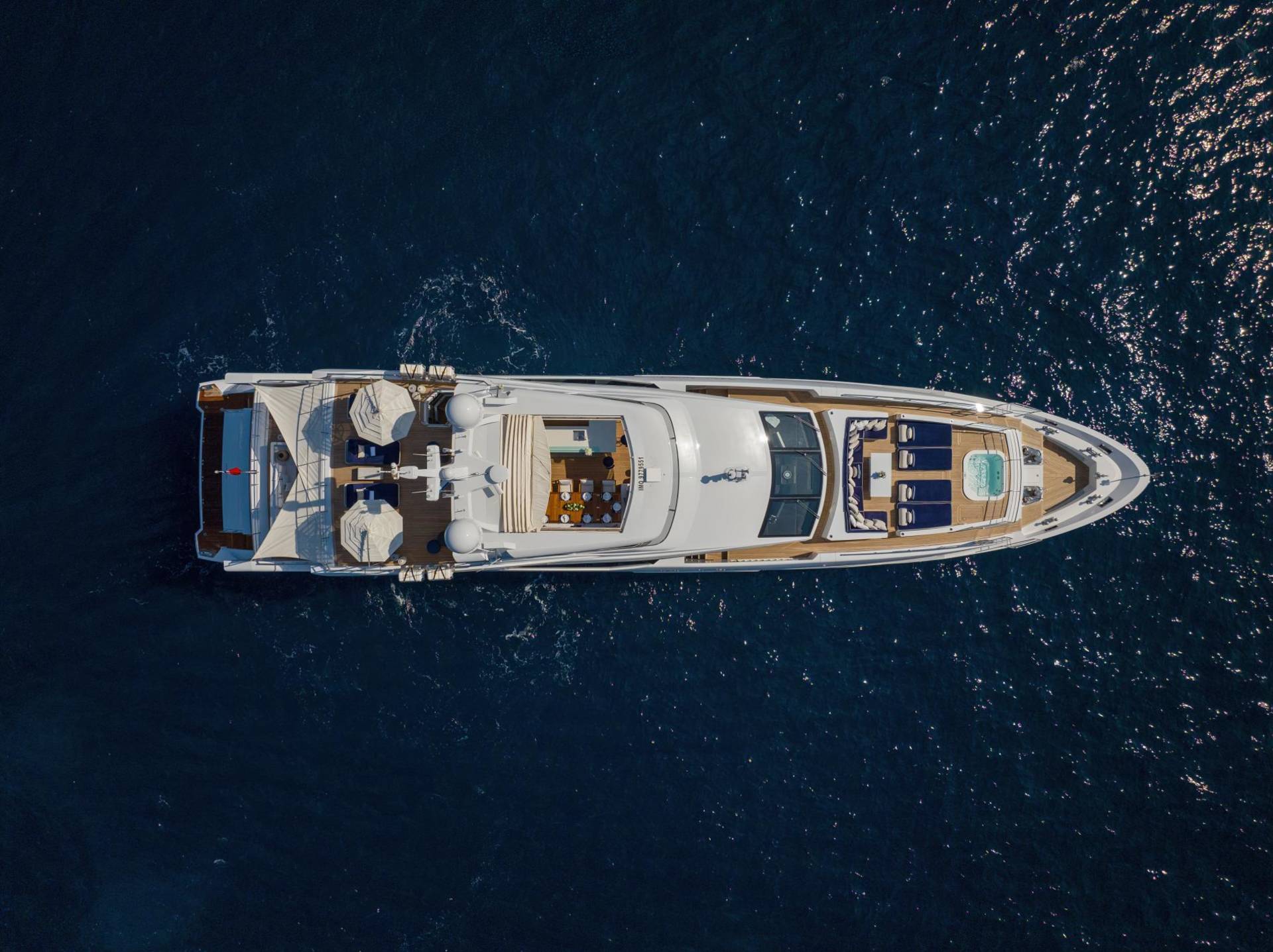 A luxurious yacht glides through the deep blue sea, offering a serene escape with its elegant decks and inviting jacuzzi.