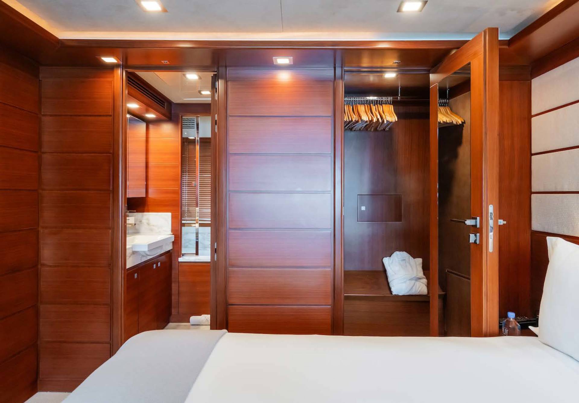 Luxurious wood-paneled stateroom features a spacious closet, elegant vanity, and plush bedding for ultimate comfort.