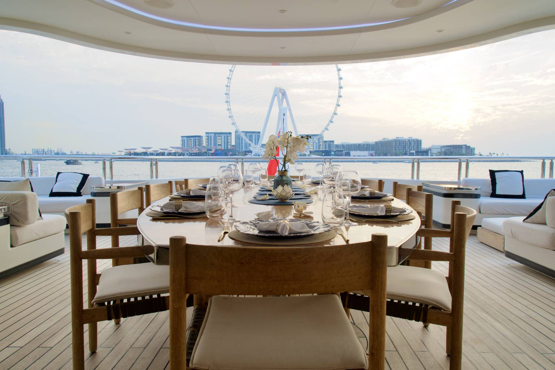 An elegant yacht dining setup awaits guests with a breathtaking view of the city skyline and a Ferris wheel.