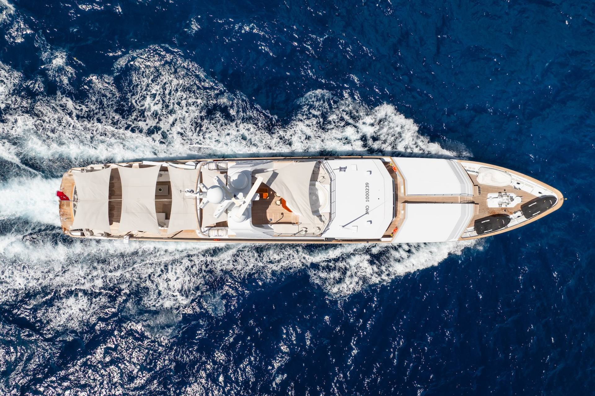 A luxurious yacht glides through the deep blue ocean, leaving a trail of white foam in its wake.