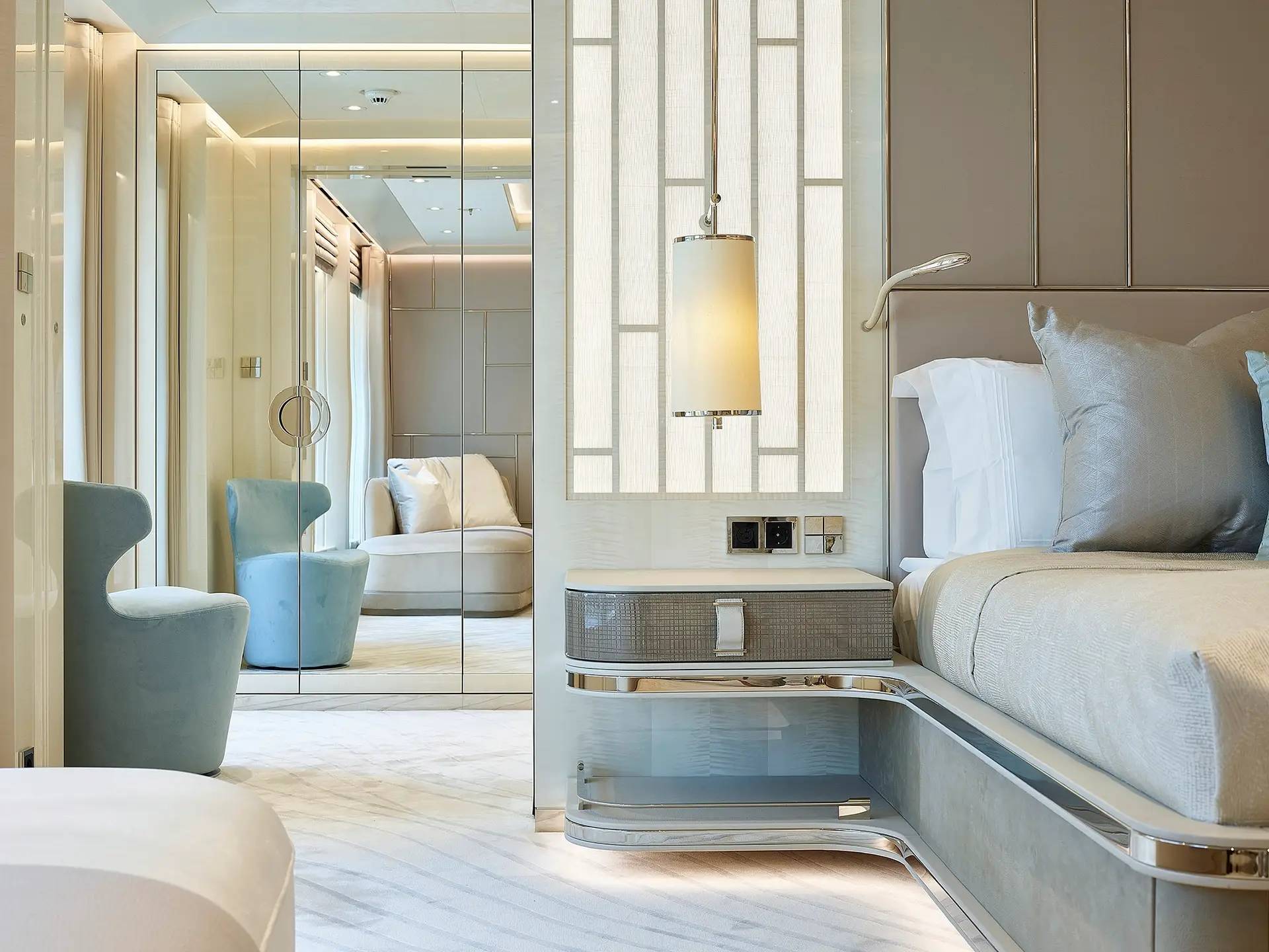 Luxurious bedroom decor features plush seating, mirrored wardrobes, and a stylish bedside table with ambient lighting.