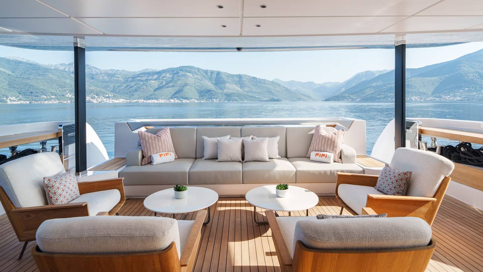 Relax on the luxurious deck of a yacht, surrounded by stunning mountain and sea views.