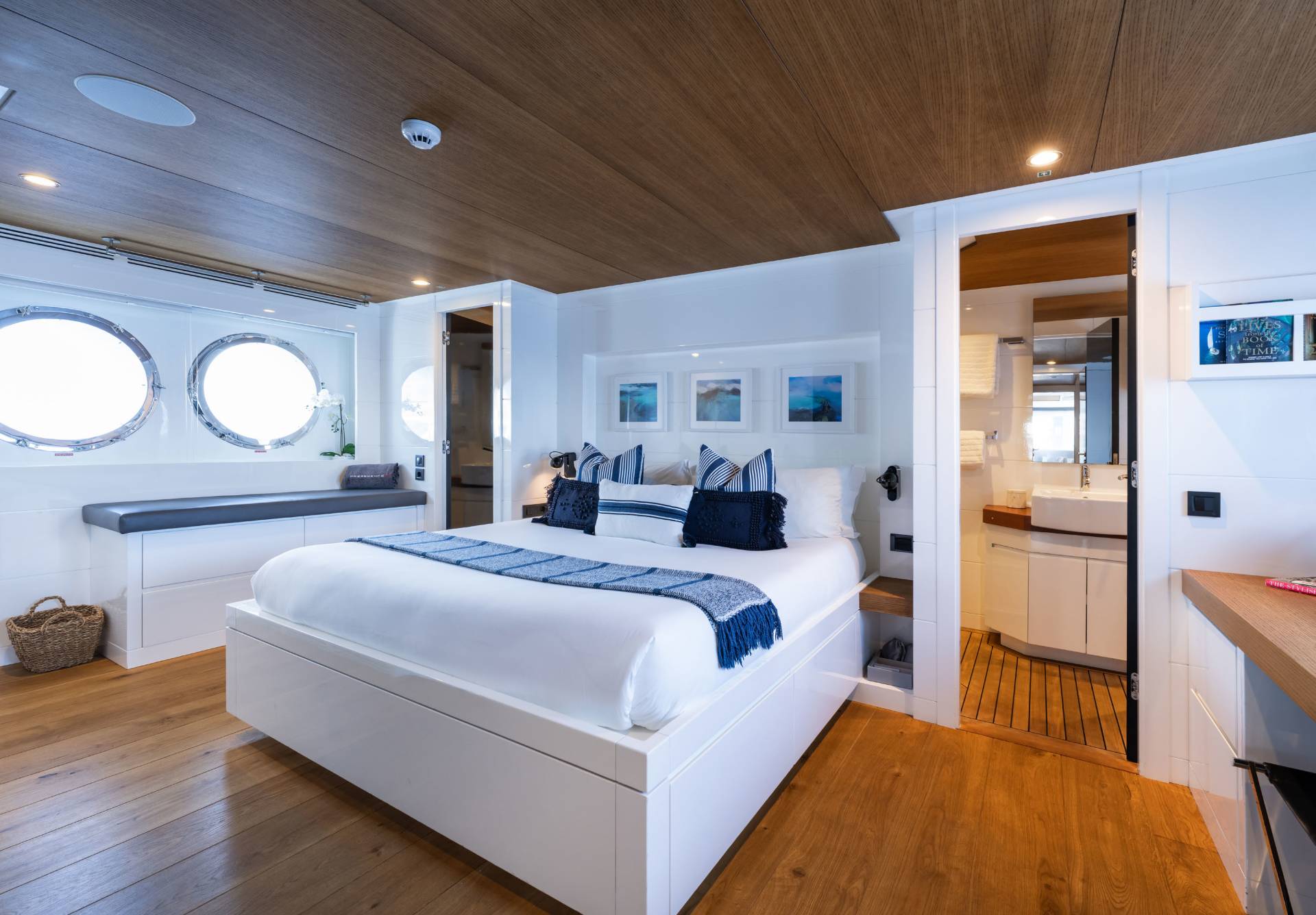 Luxurious yacht cabin features a comfortable bed, porthole windows, and an ensuite bathroom for ultimate relaxation.
