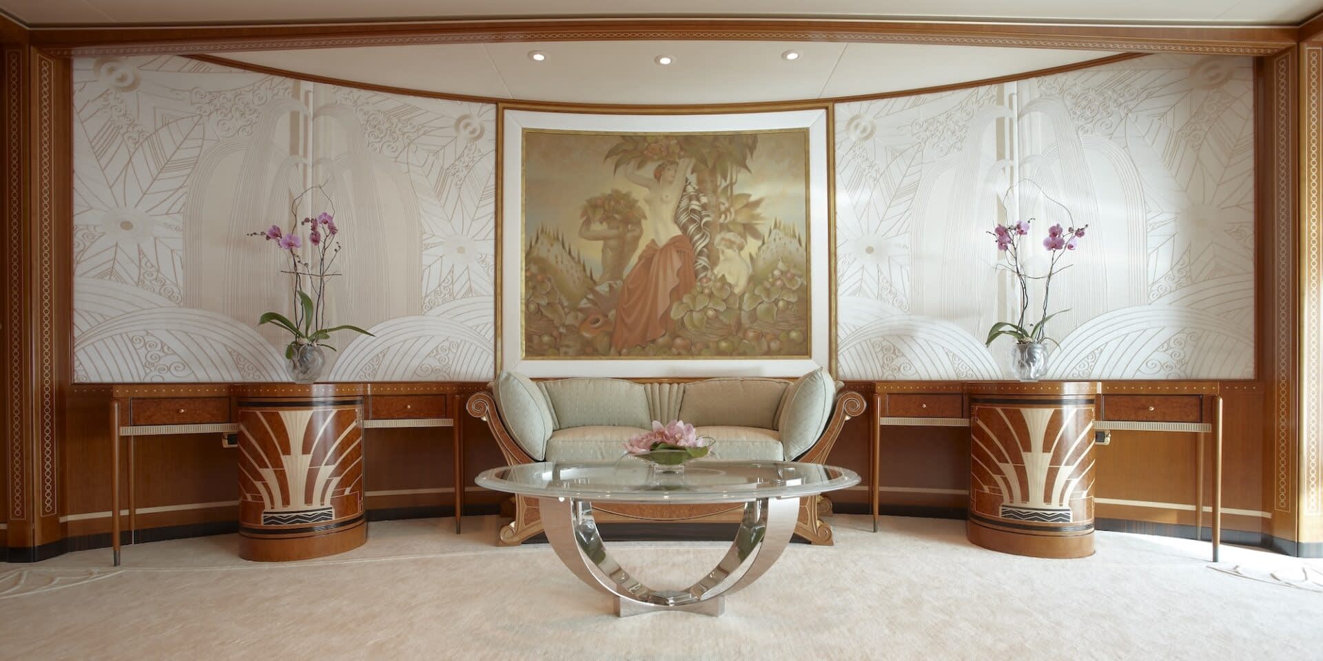 An opulent living space features a central sofa and coffee table beneath a classical painting, flanked by ornate desks and decorative wallpaper.