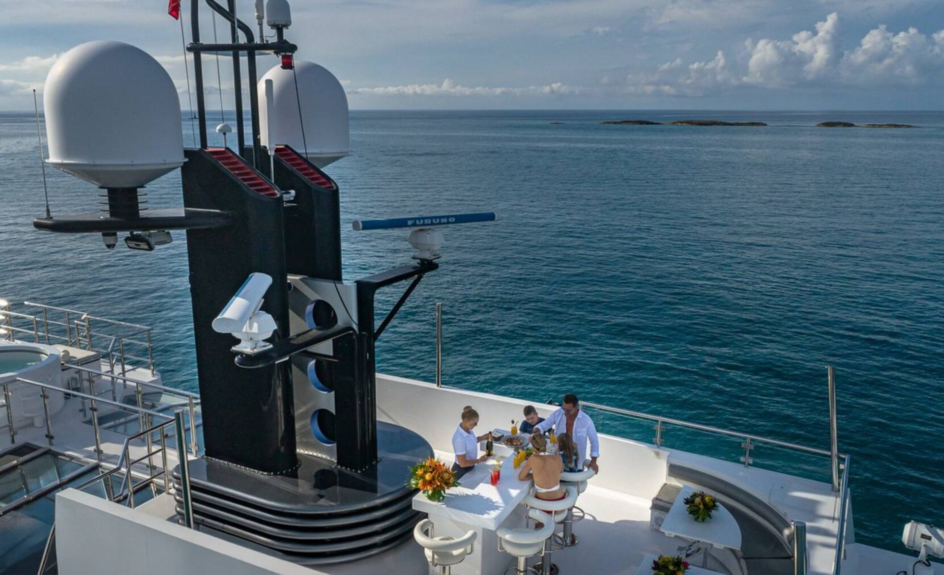 A family enjoys a meal on the deck of a luxury yacht surrounded by the tranquil blue ocean.