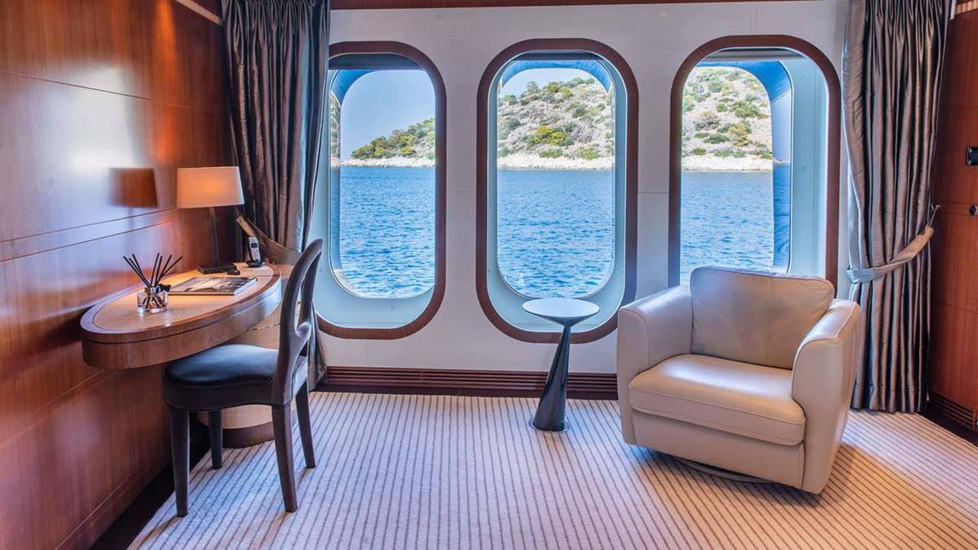 A comfortable armchair and desk offer a serene workspace with stunning ocean views through arched windows.