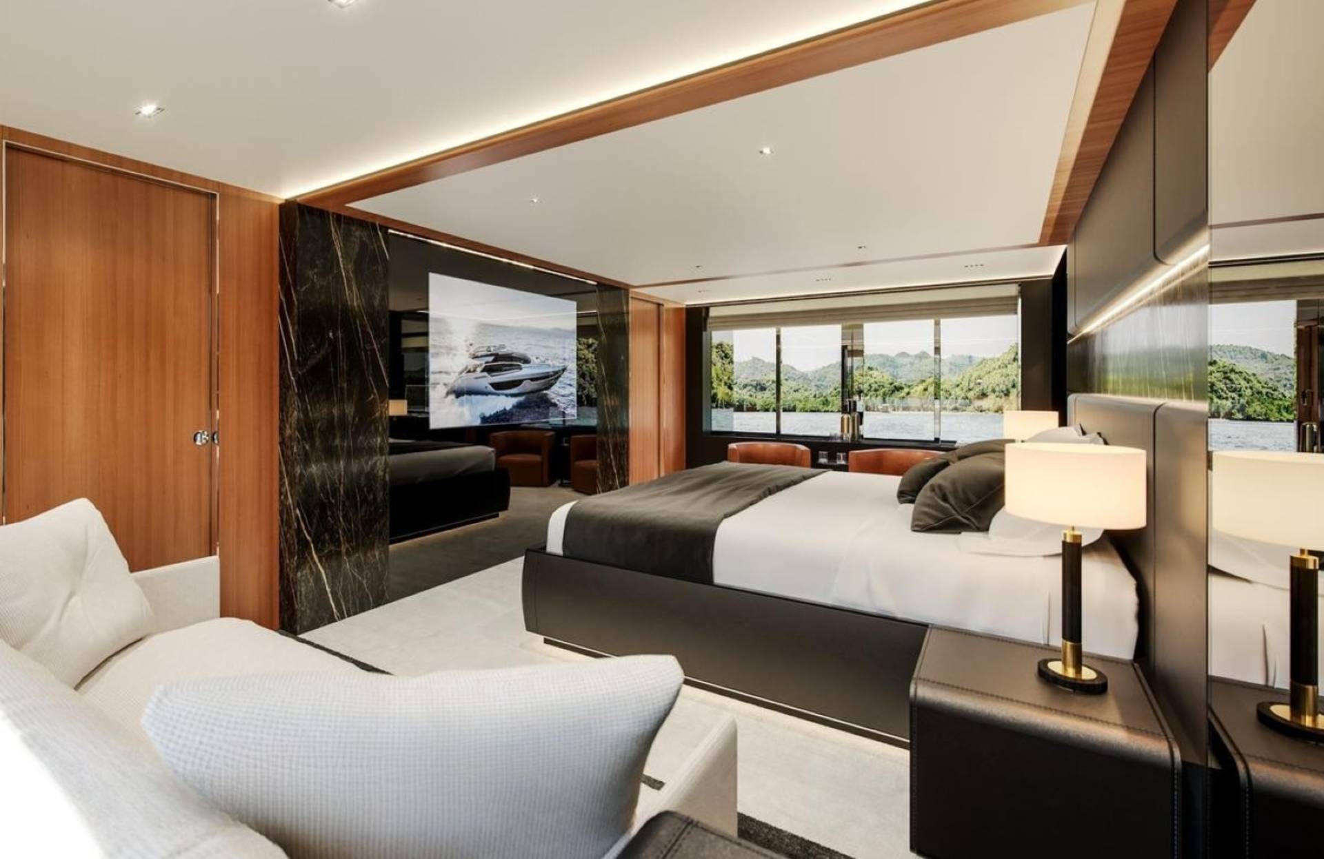 Luxurious yacht interior features a spacious bedroom with a large screen displaying a yacht and stunning water views.