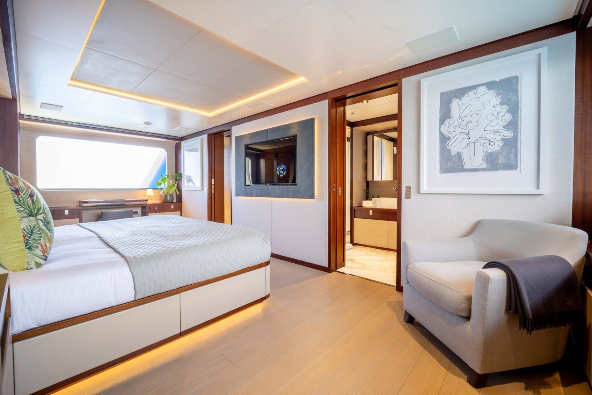 Luxurious yacht bedroom offers a serene retreat with a plush bed, modern entertainment, and an inviting armchair.