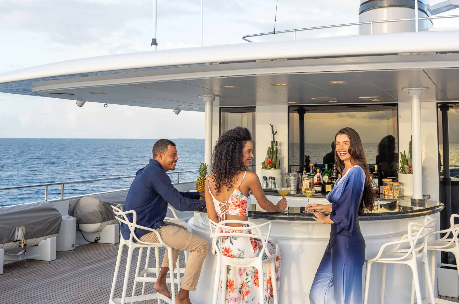 Friends enjoy cocktails at a stylish bar on a luxury yacht overlooking the ocean.