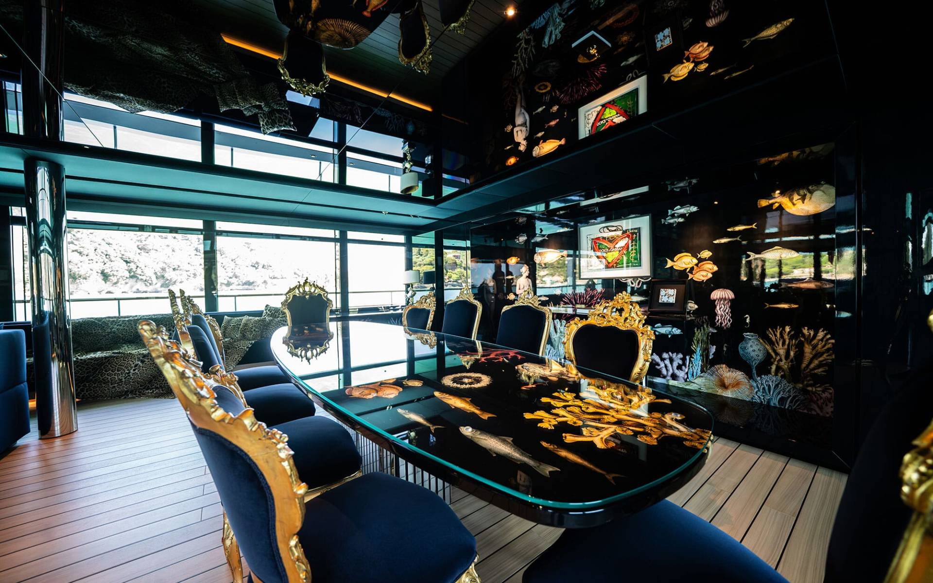 A cozy and eclectic dining room with a large wooden table surrounded by plush chairs, adorned with various decorative elements and framed artwork on the walls, and large windows offering a scenic view of the outdoors.