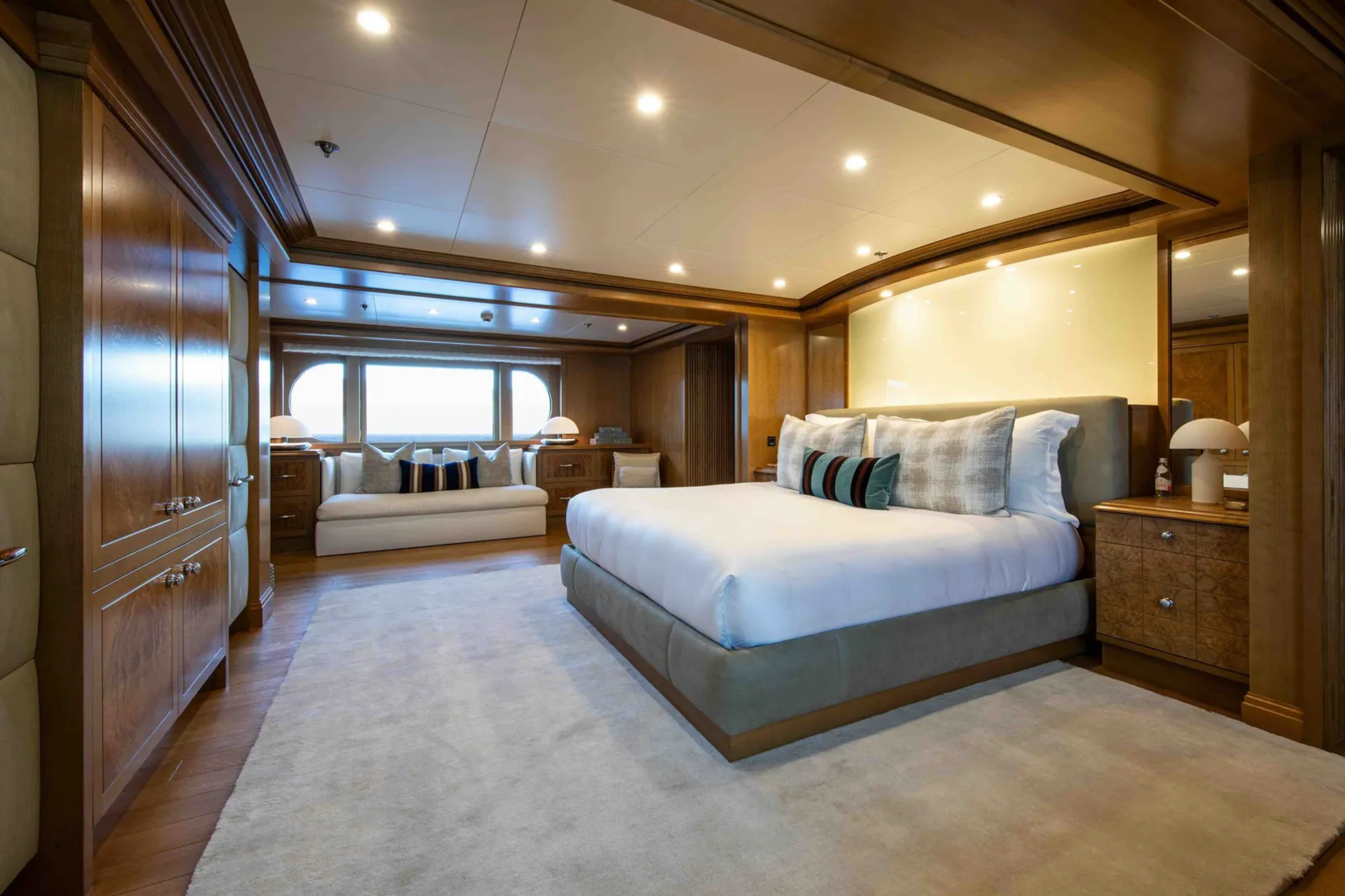 A luxurious bedroom with a large bed in the foreground and a seating area by a window in the background.