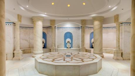 An ornate octagonal marble platform with intricate geometric patterns sits at the center of this luxurious spa's domed chamber.
