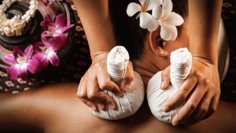 Experience ultimate relaxation with a traditional Thai herbal compress massage, adorned with fragrant plumeria flowers.