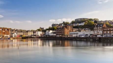 A picturesque waterfront town with historic buildings and a tranquil harbor under a clear blue sky.