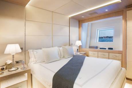 A luxurious yacht cabin offers a serene retreat with a plush bed, ambient lighting, and a captivating ocean view.