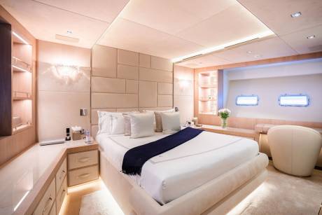 Luxurious yacht cabin features a plush bed, elegant lighting, and porthole windows offering a serene escape.