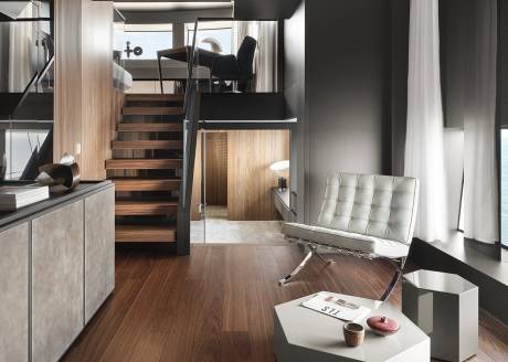 A modern yacht interior features a multi-level design with a floating staircase, minimalist furniture, and expansive windows overlooking the sea.