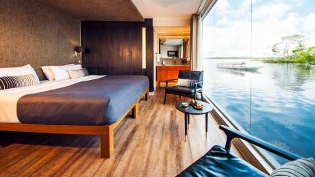 Experience serene river views from this luxurious cabin complete with a comfortable bed and elegant seating.